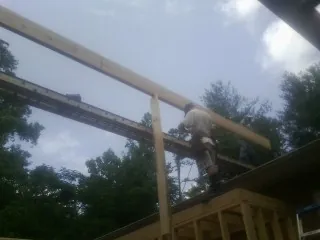 Carpenter setting a ridge beam over a new addition frame — Ice Dam Removal by Roofing Brothers in Rosanky