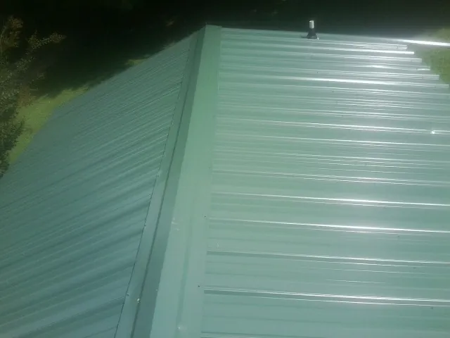 New green metal panels meeting at the ridge of a roof — Flat Roof Repair work by our crew in Rosanky