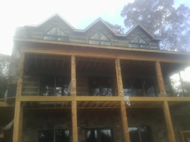 Dormers and porch framing on a large log home under construction — Roof Coating work by our crew in Rosanky