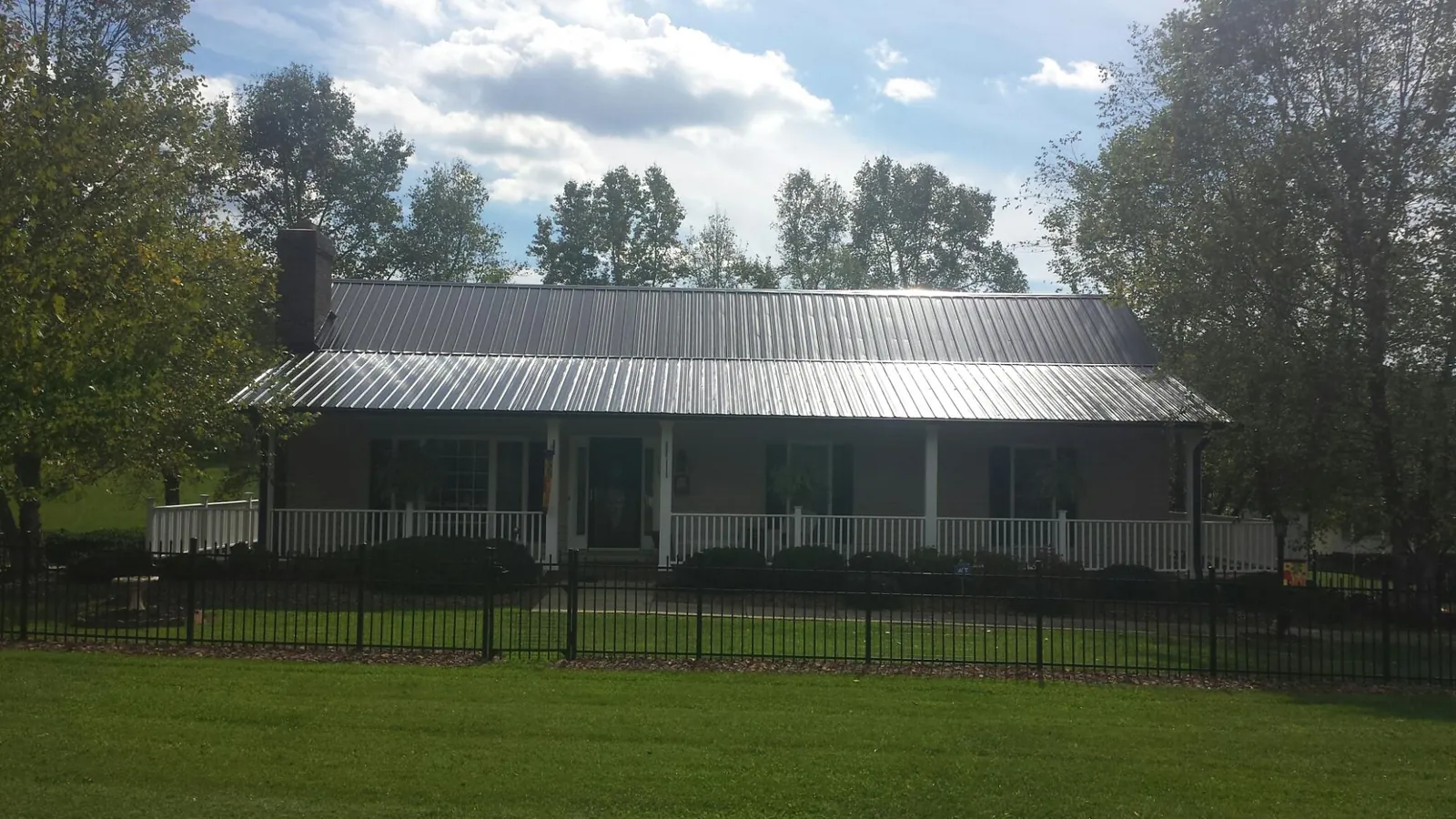 Gray metal roof on a brick ranch with a full width front porch — Gutter Guard Installation work by our crew in Rosanky