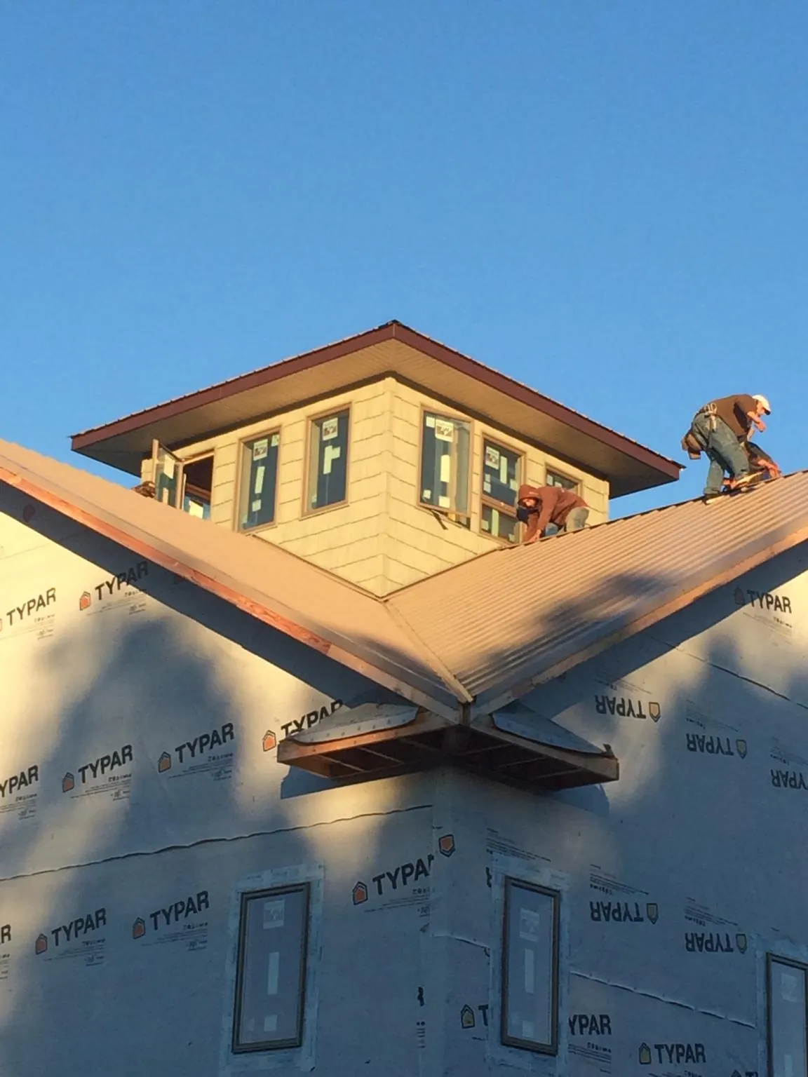 Roofers working around a rooftop cupola on a new metal roof at sunset — Roof Waterproofing in Rosanky by Roofing Brothers
